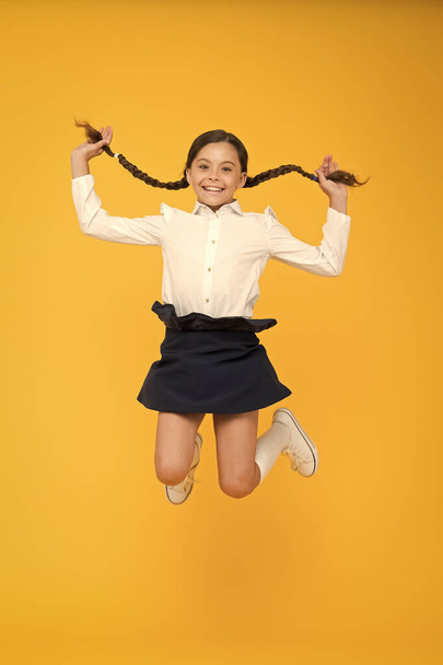 happy child jumping in school uniform. having fun. time for fun. school break. jumping and feeling free. childhood happiness. back to school. first day of study. little girl on yellow background - Foto, Imagem