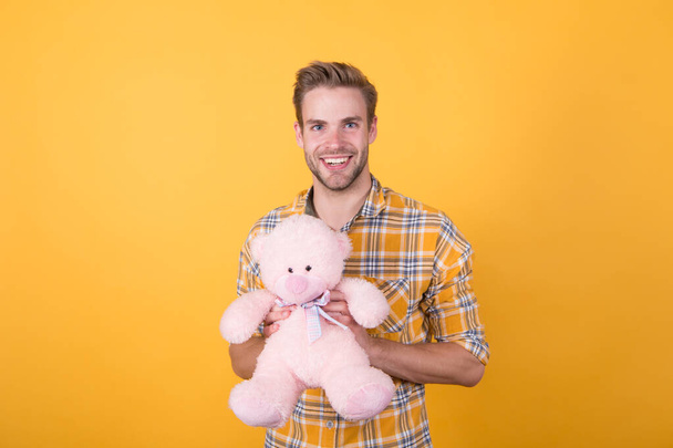 Cute teddy bear toy. Softness tenderness. Playful adult. Cute and romantic. Bearded hipster play toy yellow background. Valentines day gift. Man hug soft toy. Make surprise concept. Positive vibes - Fotó, kép