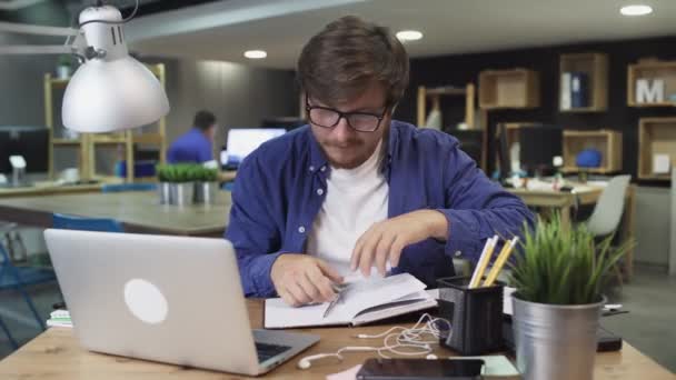 Nadšený manažer pracuje s papíry a notebookem v kanceláři. Mladý podnikatel pracující s dokumenty na svém pracovišti, časový odstup - Záběry, video