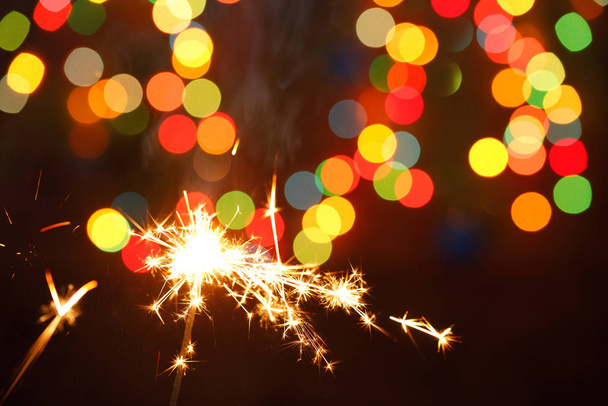 beautiful sparklers on the background of a garland. beautiful holiday card for the New Year. - Photo, Image
