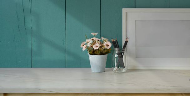 Gehakt schot van comfortabele werkplek met kantoorbenodigdheden en kopieerruimte op witte tafel en lichtblauwe wand achtergrond - Foto, afbeelding