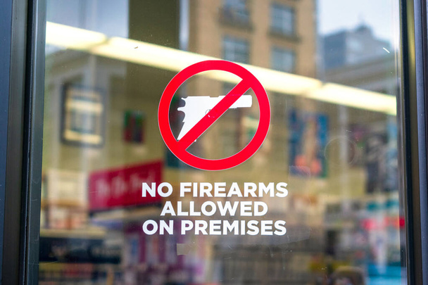 ガラスの入り口のドアの敷地内の標識に許可されていない銃は、武器が許可されていないことを知らせる. - 写真・画像