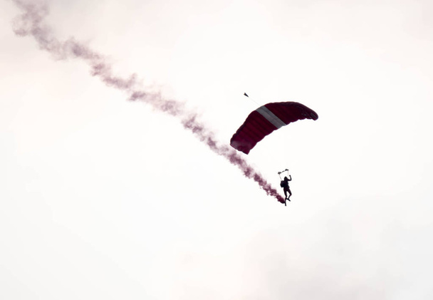 Силуэт парашютный трюк несосредоточен и размыт во время скольжения в
 - Фото, изображение