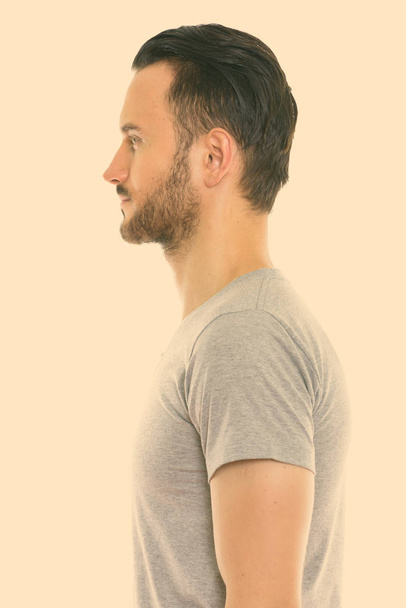 Studio shot of young handsome bearded man isolated against white background - Photo, image