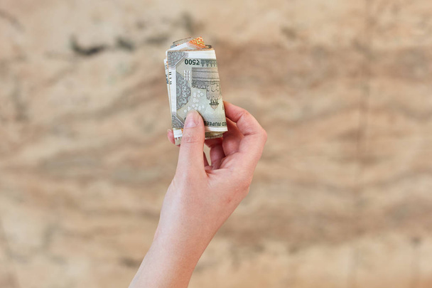 Holka drží v ruce srolovanou bankovku 500 indiánských rupií. - Fotografie, Obrázek
