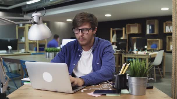 Assistent brengt koffie naar jonge baas terwijl hij werkt op laptop - Video