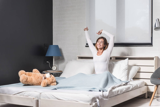 Happy young girl stretching in bed after wake up - Φωτογραφία, εικόνα