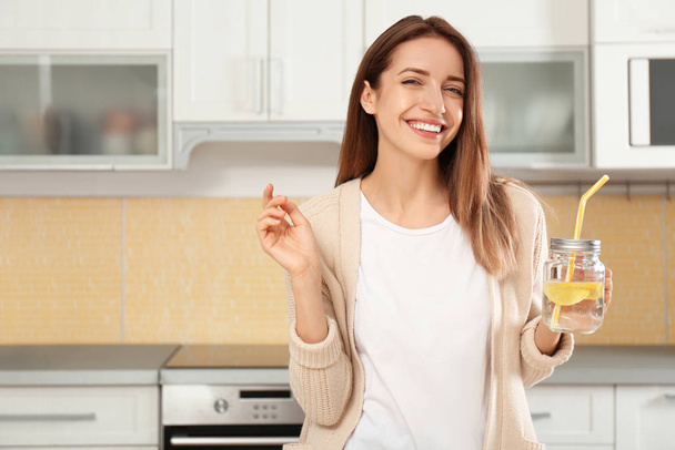 Νεαρή γυναίκα με χυτό βάζο λεμονόνερο στην κουζίνα - Φωτογραφία, εικόνα