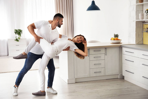 Lovely young couple dancing in kitchen at home - 写真・画像