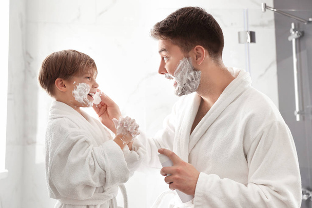Dad applying shaving foam onto son's face in bathroom - Photo, Image