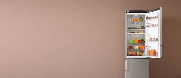 Open fridge full of food on color background with space for text - Fotoğraf, Görsel