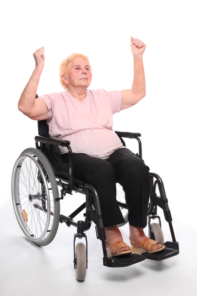 üzerinde beyaz bir tekerlekli sandalyede oturan yaşlı belden aşağısı felçli kadın. - Fotoğraf, Görsel