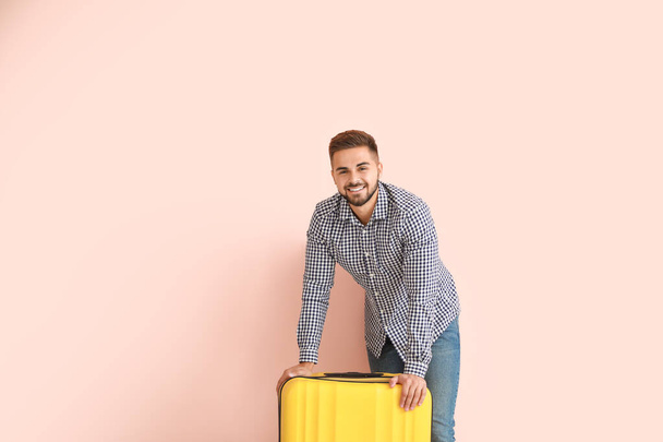 Young man with luggage on color background - Zdjęcie, obraz