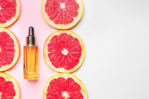 Botella de aceite esencial y rodajas de pomelo sobre fondo de color
 - Foto, Imagen