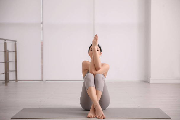 Young woman practicing eagle asana in yoga studio. Garudasana po - Fotó, kép