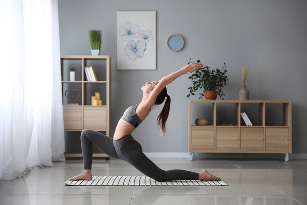 Piękna młoda kobieta ćwiczy jogę w domu - Zdjęcie, obraz