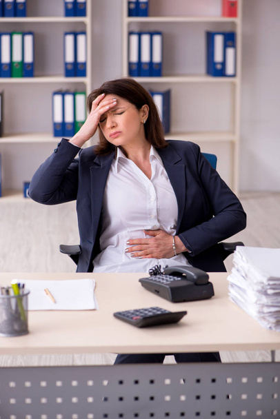 Middle-aged female employee suffering in the office - Photo, Image