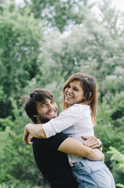 Happy couple kissing and hugging in nature. Young man and woman  - 写真・画像