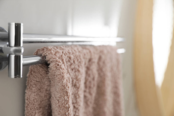 Holder with clean towel on light wall in bathroom, closeup - Zdjęcie, obraz