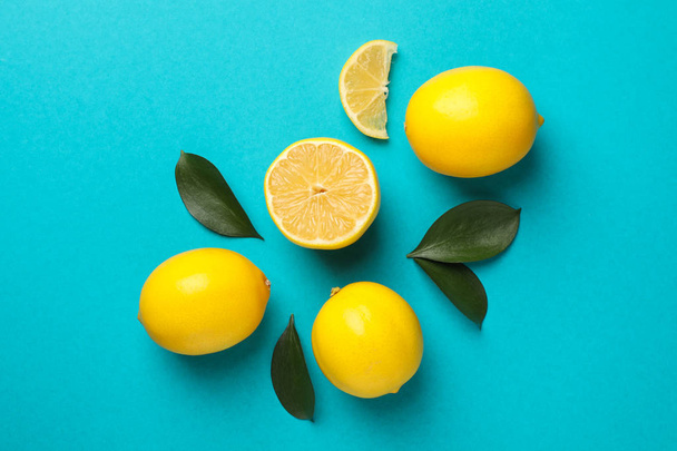Juicy lemons and leaves on turquoise background, top view - Zdjęcie, obraz