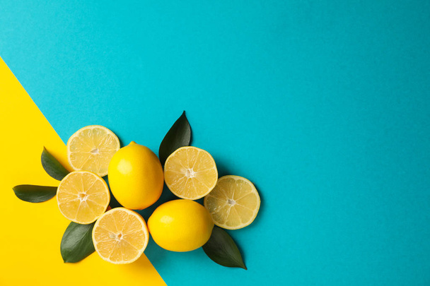 Juicy lemons and leaves on two tone background, top view - Fotó, kép