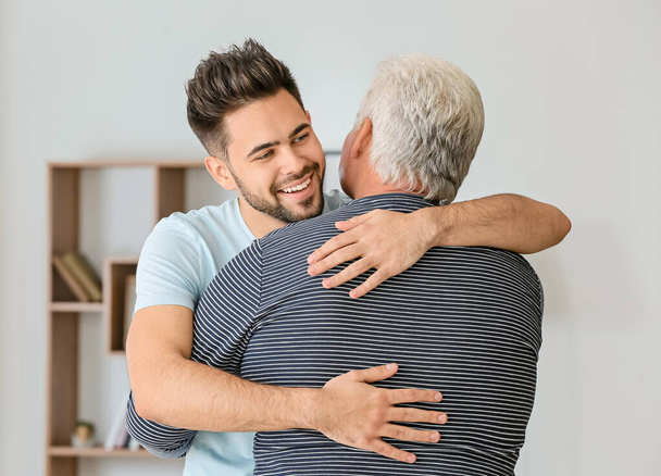 Young man and his father hugging at home - Foto, Imagen