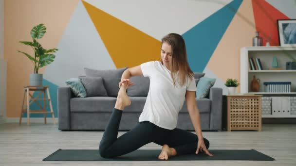 Slow motion of young woman stretching body with yoga exercises in modern house - Video