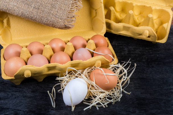 Eieren in kartonnen eierschaal en naast op donkere ondergrond - Foto, afbeelding