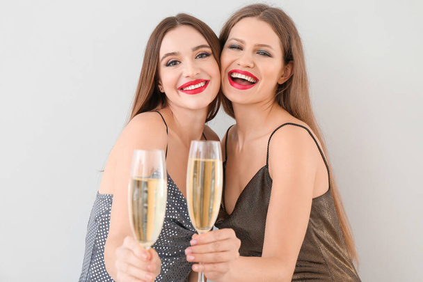 Beautiful young women with champagne on light background - Photo, Image
