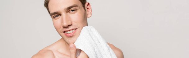smiling sexy man with muscular torso holding cotton towel isolated on grey, panoramic shot - Foto, afbeelding