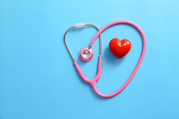 Stethoskop und rotes Herz auf farbigem Hintergrund. Kardiologie-Konzept - Foto, Bild