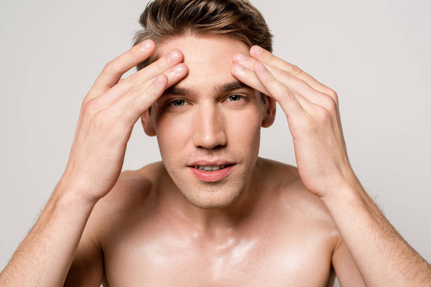 sexy Mann mit muskulösem Oberkörper und perfekter Haut berühren Gesicht isoliert auf grau - Foto, Bild