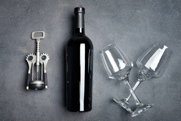 Bottle of wine, glasses and corkscrew on grey background - Foto, afbeelding