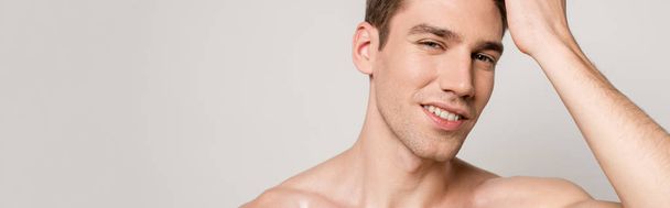 smiling sexy man with muscular torso touching hair isolated on grey, panoramic shot - Foto, immagini