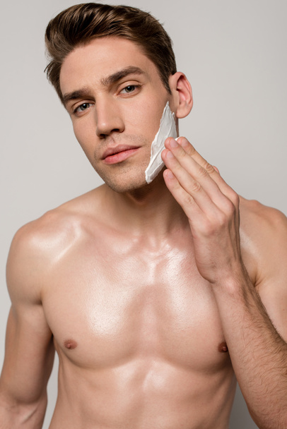 σέξι άνδρας με μυϊκό κορμό εφαρμογή αφρού ξυρίσματος απομονώνονται σε γκρι - Φωτογραφία, εικόνα