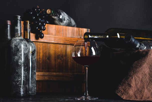 Garrafas e copo de vinho na mesa na adega
 - Foto, Imagem