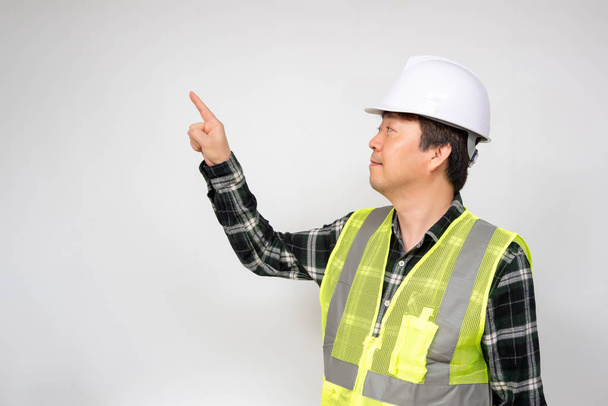 Aasian keski-ikäinen mies vaaleanvihreä työ liivi ja valkoinen turvallisuus hattu
. - Valokuva, kuva