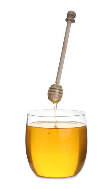 Honey dripping from wooden dipper into jar isolated on white - 写真・画像