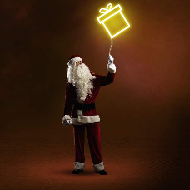 Санта Клаус держит блестящий подарок
 - Фото, изображение