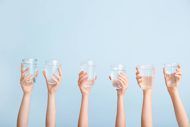 Female hands with glasses of water on color background - Valokuva, kuva