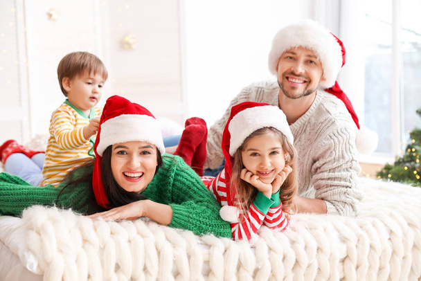 Счастливая семья отдыхает в спальне в Рождество
 - Фото, изображение