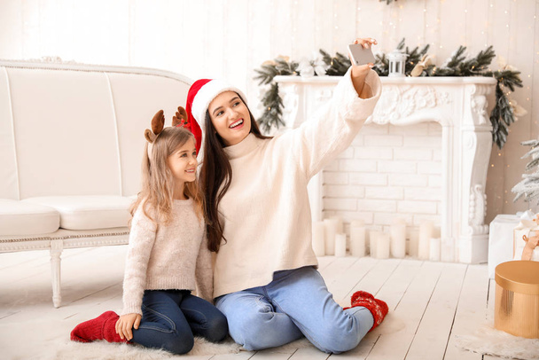 Mutlu anne ve küçük kızı Noel arifesinde evde selfie çekiyorlar. - Fotoğraf, Görsel