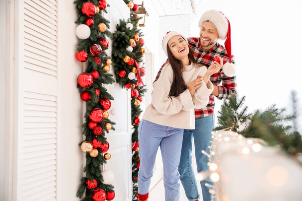 Щаслива пара прикрашає ганок на Різдво
 - Фото, зображення
