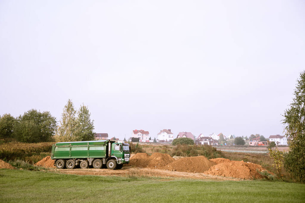 Ein großer 70-Tonnen-Kipper brachte Sand auf eine neue Baustelle, um Land hinzuzufügen - Foto, Bild