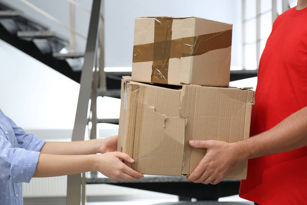 Koerier geeft beschadigde kartonnen dozen aan klant binnen, close-up. Slechte kwaliteit bezorgservice - Foto, afbeelding