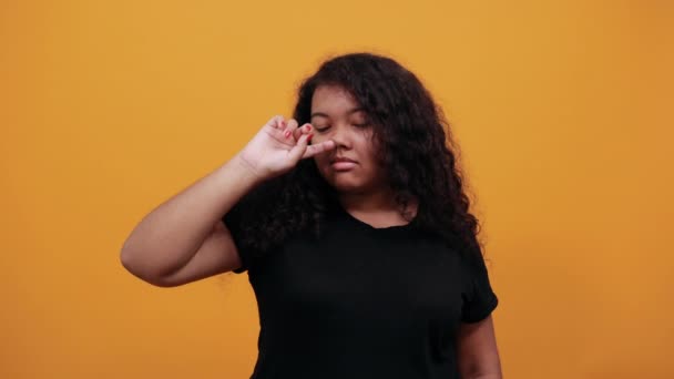 Mujer joven afroamericana con exceso de peso en la nariz, mirando a la cámara
 - Metraje, vídeo