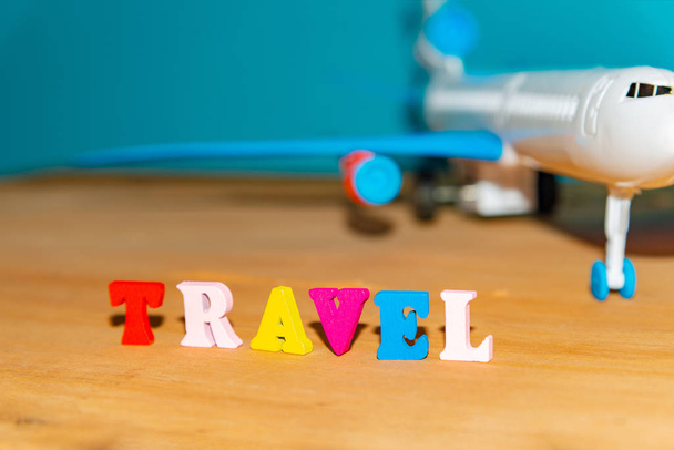 Matkailu ja matkailu käsite, lelu lentokone ja väri kirjaimet puinen tausta
. - Valokuva, kuva