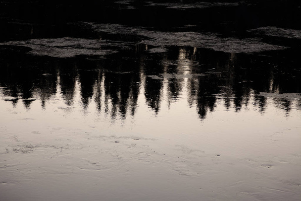 Bäume spiegeln sich in eisigem Wasser, wenn die Sonne untergeht - Foto, Bild