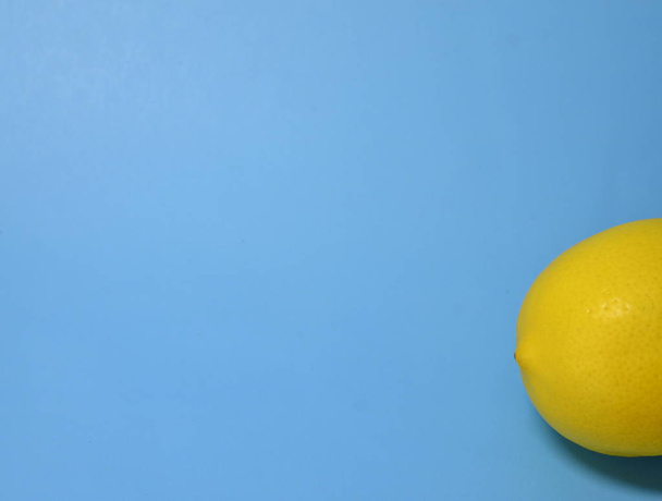 Backgrounds and textures. On a blue background lies a yellow appetizing citrus lemon. - Foto, Imagem