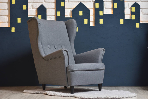 Меблі для дитячої кімнати сірий стілець для домашнього інтер'єру на тлі білої цегляної стіни з гірляндою і силуетом міста
 - Фото, зображення